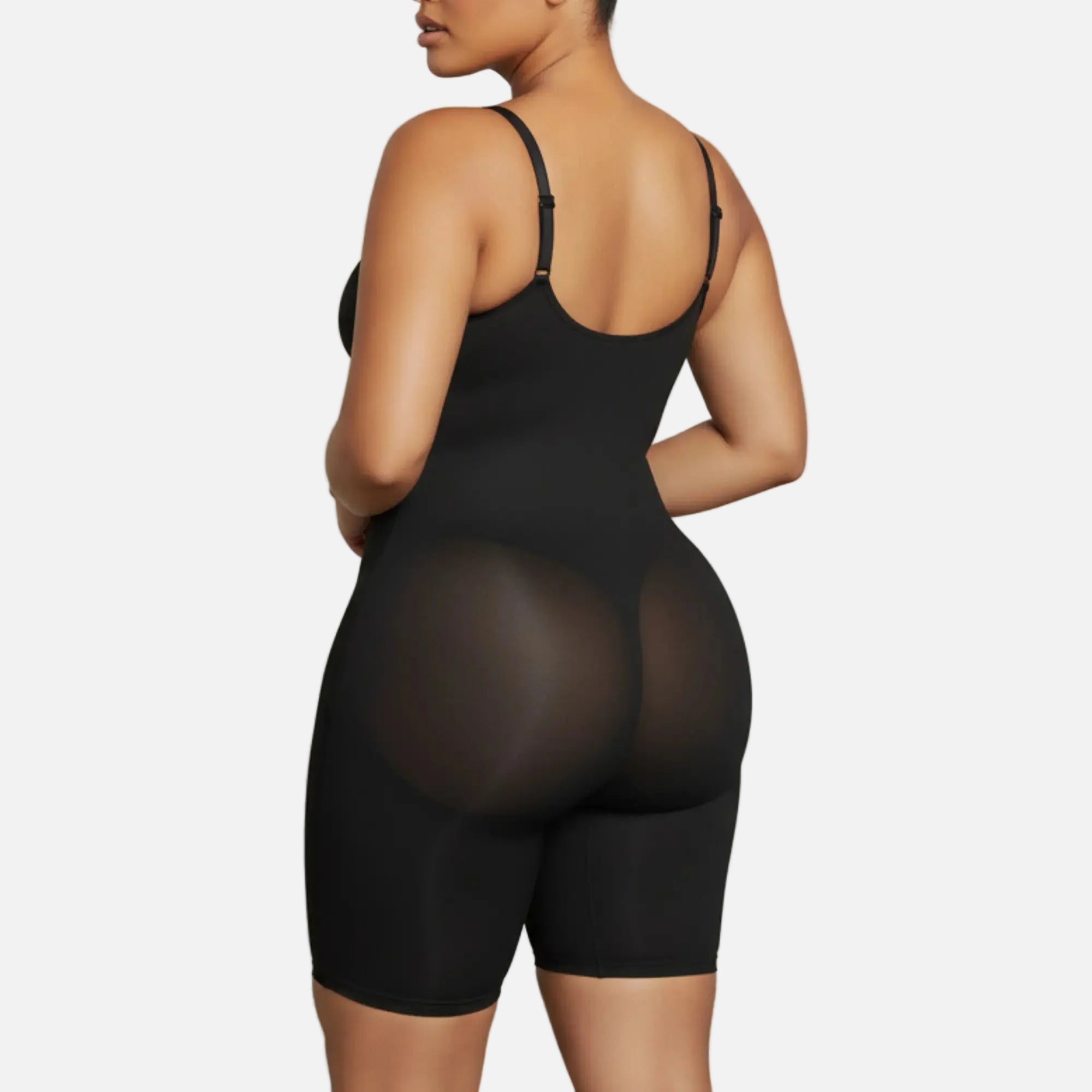 Person wearing a black bodysuit against a plain background